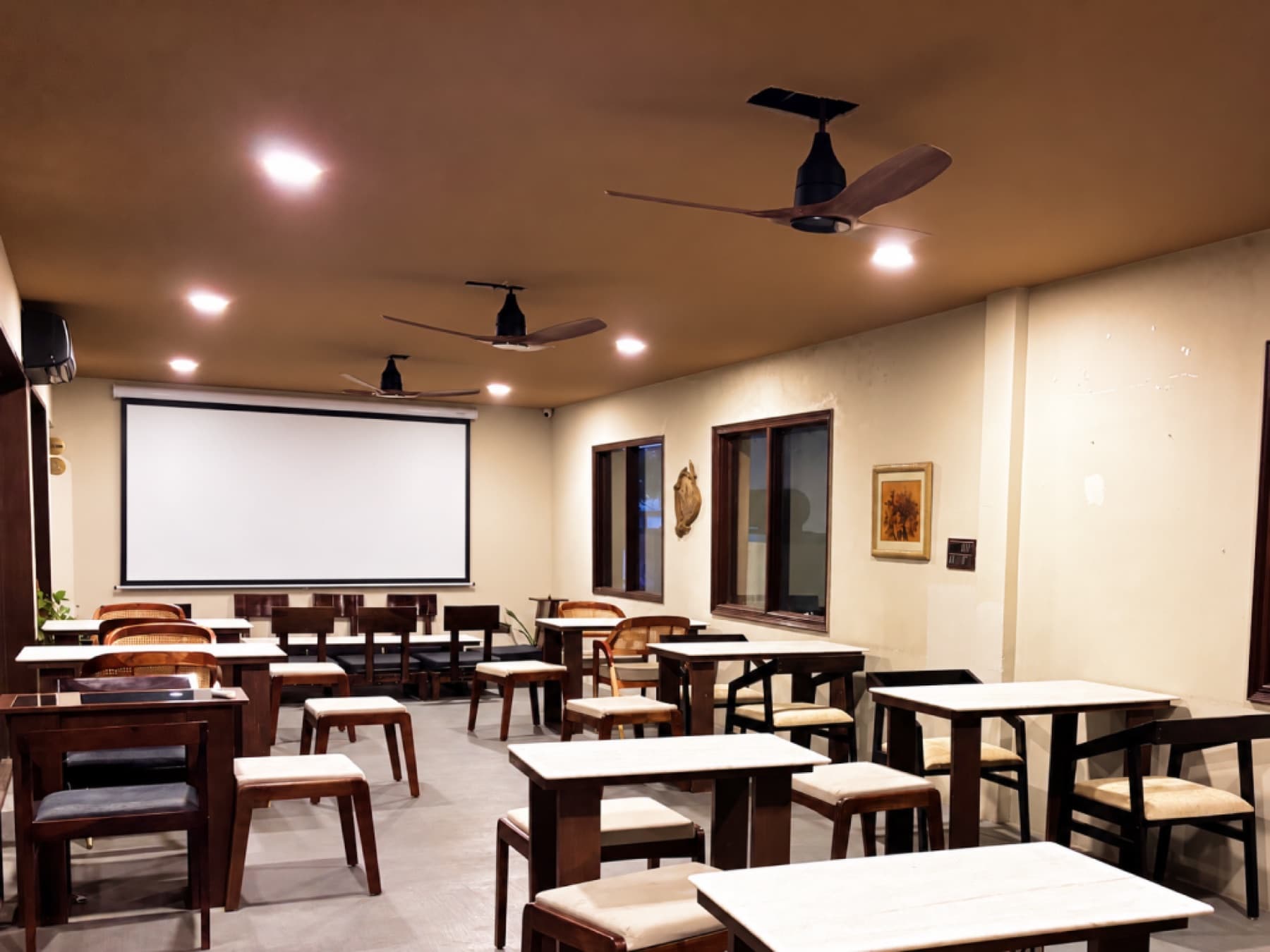 First-floor event space wide view with presentation screen and projector setup